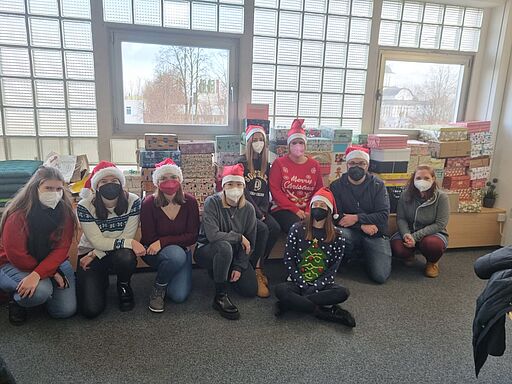 Foto von Schüler der Fachakademie für Sozialpädagogik mit Weihnachtsmützen und Schuhkarton-Geschenken